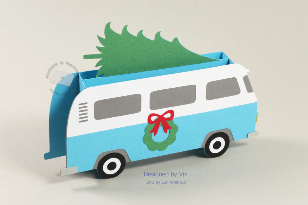 alter Bus in blau und weiß mit Tannenbaum auf dem Dach und seitlich eine grünerkranz mit roter Schleife als Pop-Up-Karte; Seitenansicht schräg