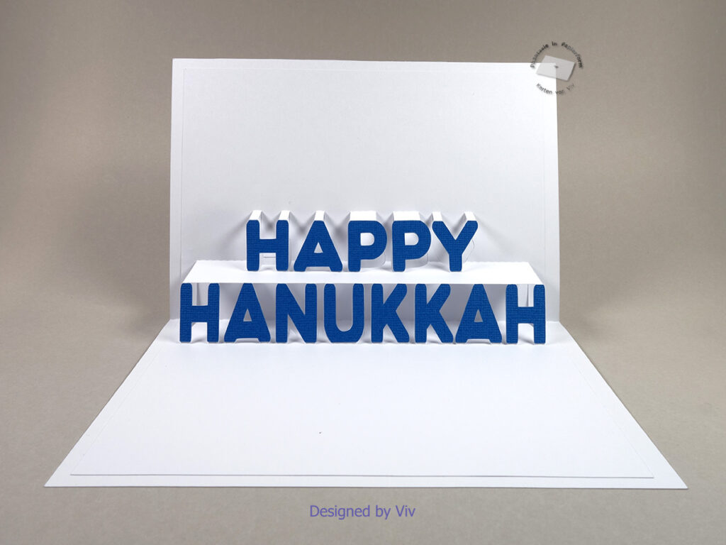 An open card with the pop up letters spelling Happy Hanukkah and blue letters glued to the pop up detail.